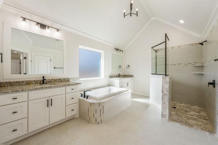 Bathroom featuring vanity, ornamental molding, a chandelier, vaulted ceiling, and independent shower and bath