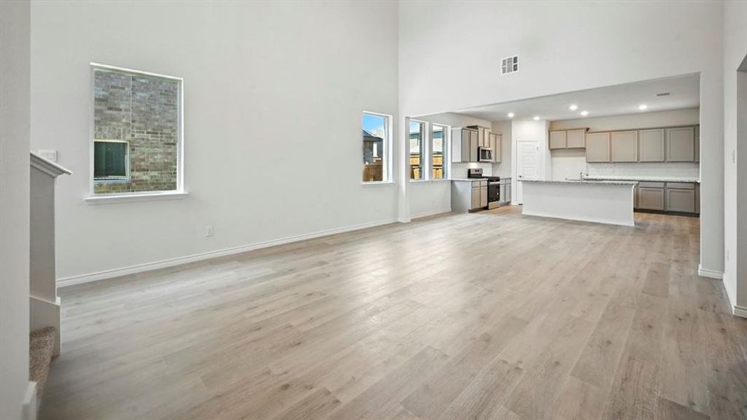 Unfurnished living room with light wood-style flooring and a high ceiling Unfurnished living room with light wood-style flooring and a high ceiling