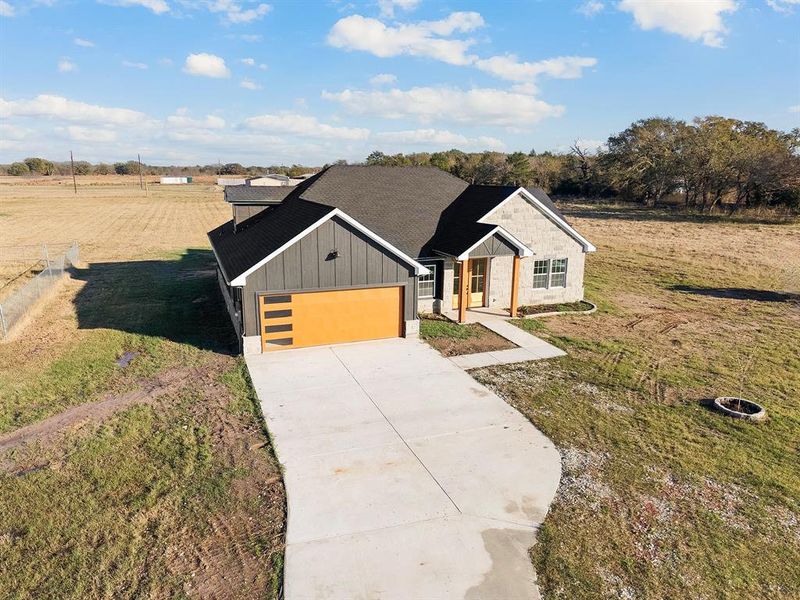 View of front of home featuring board and batten siding, a front lawn, concrete driveway, and roof with shingles