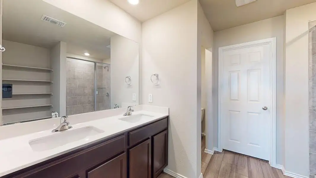 Bathroom featuring double vanity, light wood-type flooring, a stall shower, and recessed lighting