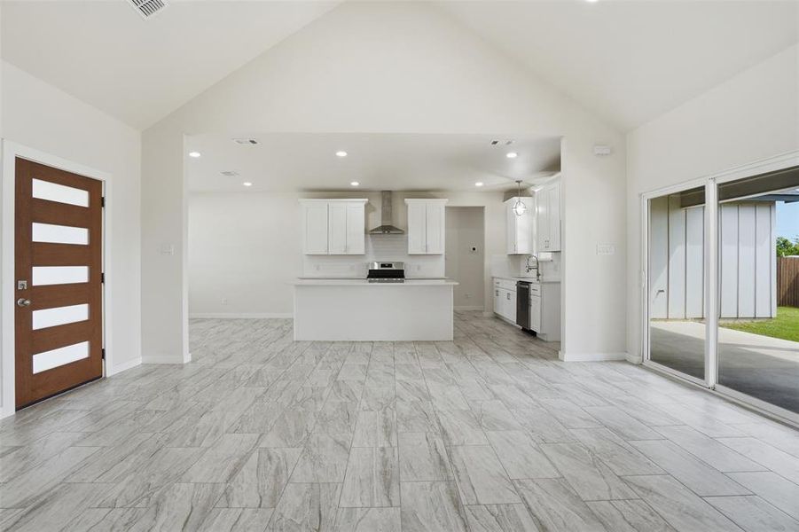 Spacious living area featuring light gray wood-look flooring and soaring vaulted ceilings