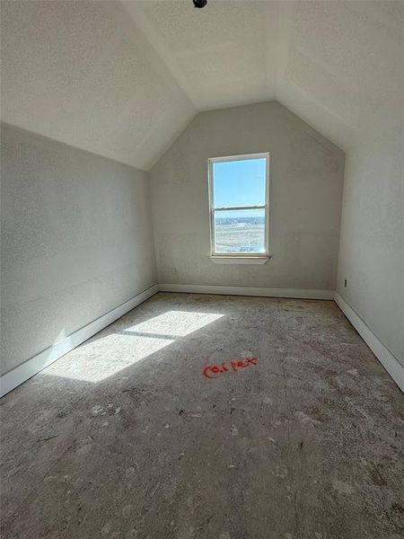 Bonus room with vaulted ceiling, baseboards, and a textured ceiling