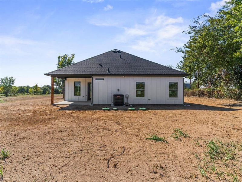 Rear view of house with a patio, roof with shingles, and board and batten siding