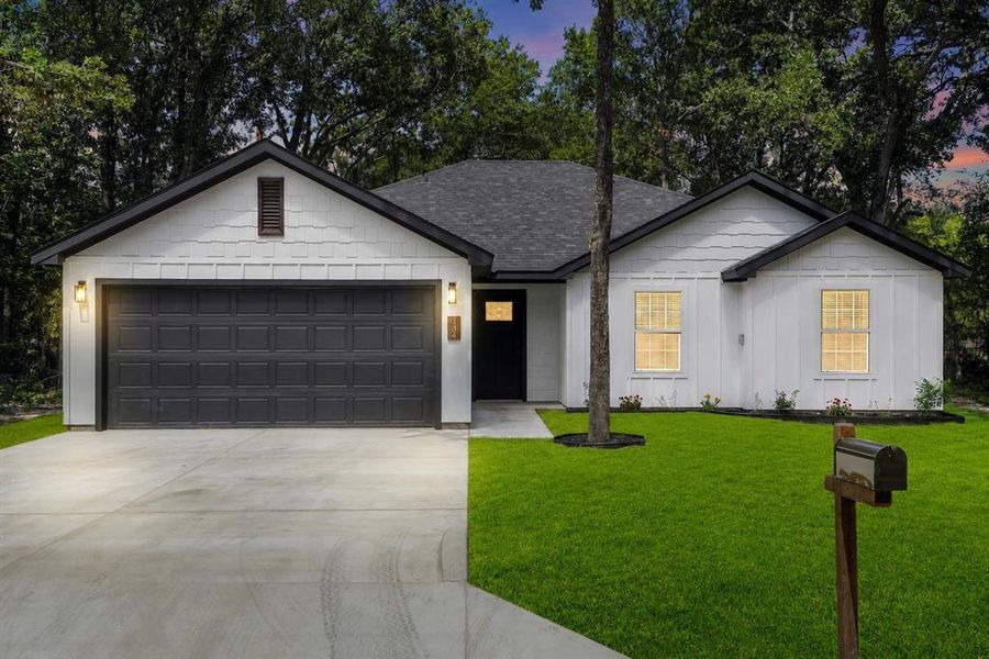 Contemporary single-story residence featuring white siding, a dark roof, and a two-car garage Contemporary single-story residence featuring white siding, a dark roof, and a two-car garage
