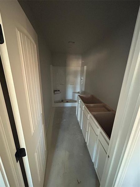 Full bathroom featuring concrete flooring, double vanity, and a garden tub