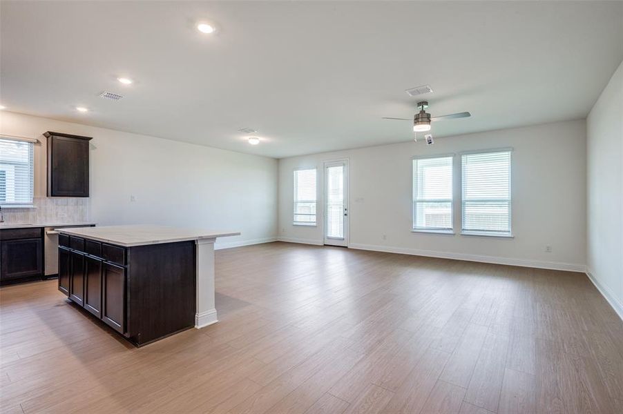 Kitchen featuring a ceiling fan, light wood-style floors, dark brown cabinets, open floor plan, and a center island
