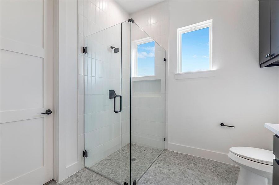 Modern bathroom featuring a frameless glass shower enclosure with matte black hardware, white subway tile shower surround, and gray mosaic tile flooring Modern bathroom featuring a frameless glass shower enclosure with matte black hardware, white subway tile shower surround, and gray mosaic tile flooring
