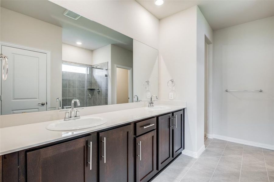 Bathroom with tile patterned floors, a shower with door, and dual bowl vanity