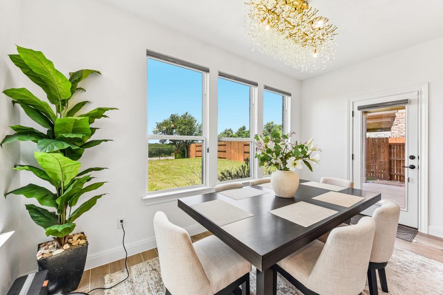 A radiant chandelier illuminates this dining space with its scenic yard view.