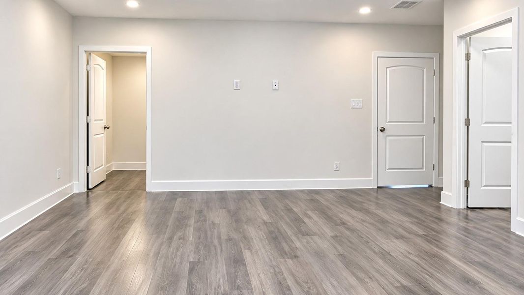 Spacious primary bedroom with sleek floors, neutral walls.