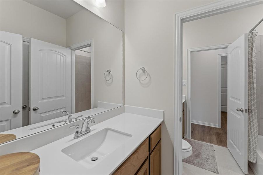 Bathroom vanity featuring a single basin sink, chrome faucet, and expansive wall-mounted mirror