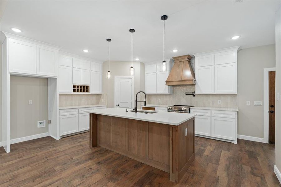 Kitchen with white cabinetry, custom range hood, decorative backsplash, a kitchen island with sink, and recessed lighting