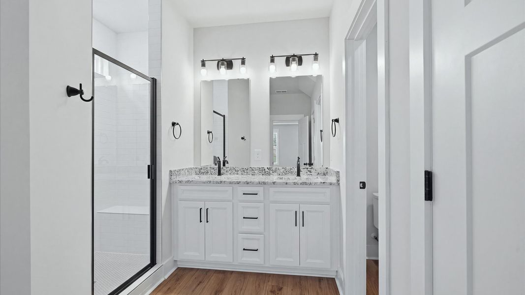 Elegant primary bathroom featuring a spacious walk-in shower and dual vanity in this first-class DRB Homes design