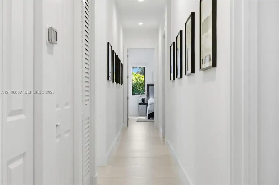 Hallway featuring light-toned tile flooring, recessed ceiling lighting, and louvered-style bi-fold closet doors
