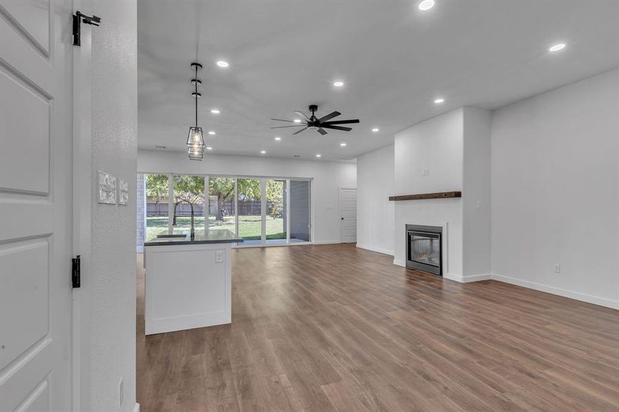 Unfurnished living room with hardwood / wood-style flooring, ceiling fan, and sink