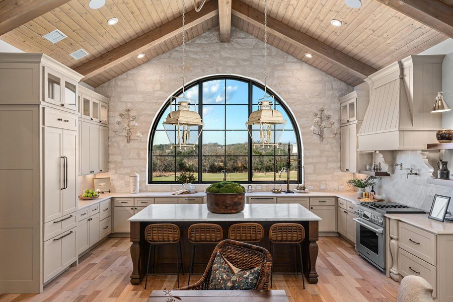 Kitchen with light stone counters, glass insert cabinets, high end appliances, tasteful backsplash, and recessed lighting