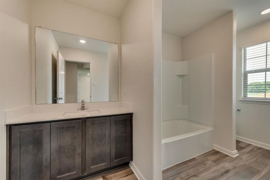 Bathroom featuring hardwood / wood-style floors, vanity, and tub / shower combination