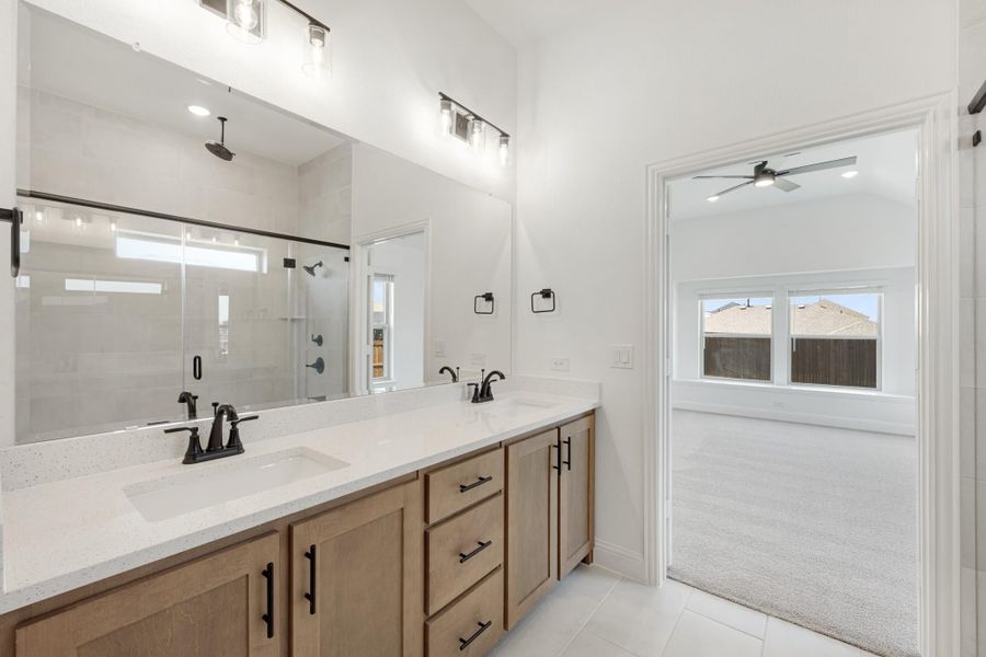 Master bathroom with double vanity, quartz countertops, wood cabinets, glass shower, and large mirror with modern black fixtures. Master bathroom with double vanity, quartz countertops, wood cabinets, glass shower, and large mirror with modern black fixtures.