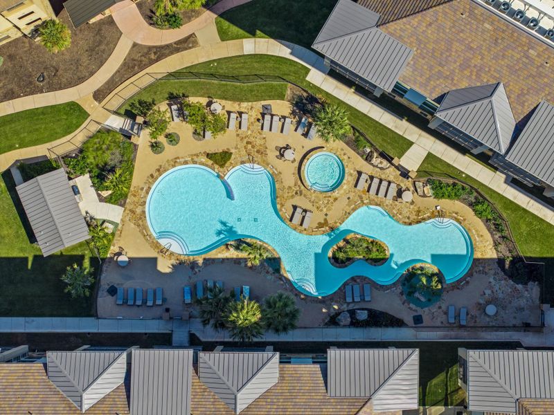 An aerial perspective reveals a vibrant community pool with inviting lounge areas, framed by pathways and manicured landscaping.