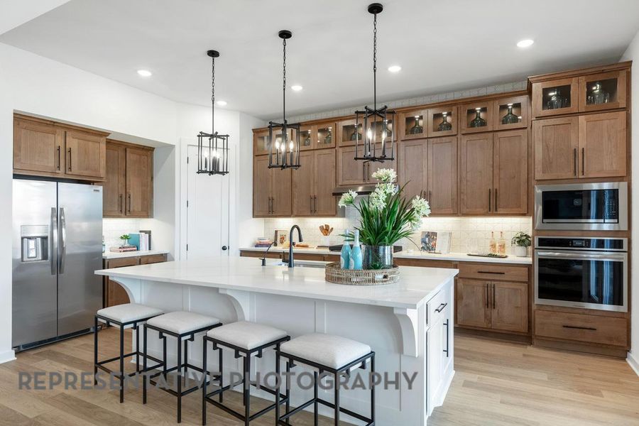 Kitchen featuring appliances with stainless steel finishes, decorative backsplash, brown cabinetry, light wood finished floors, and recessed lighting