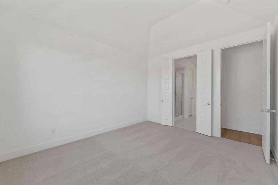 The primary bedroom opens to the bathroom through elegant double doors, adding a touch of luxury and flow to the space.