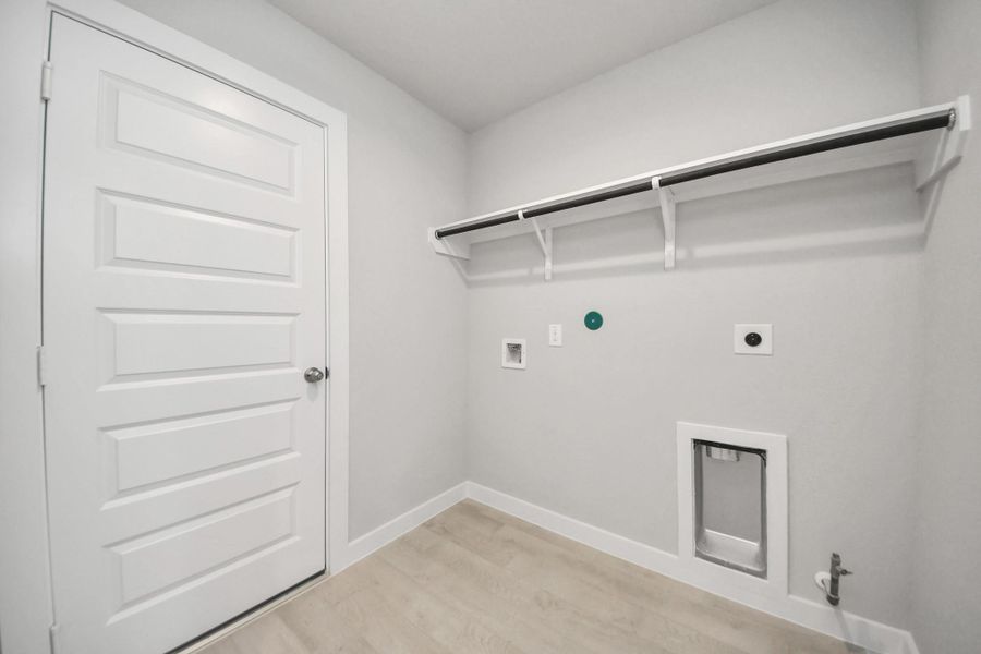 A perfect blend of functionality and comfort. Capture the essence of easy living with a first-floor laundry room, thoughtfully equipped with shelving for effortless organization. Both electric and gas connections available. Sample photo of completed home with similar floor plan. Actual colors and selections may vary.