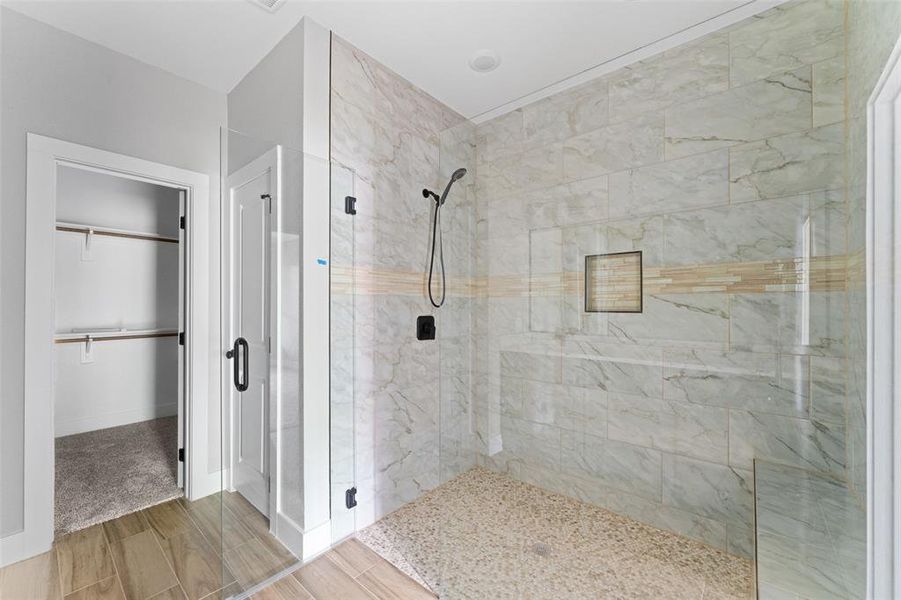 Bathroom with a stall shower, wood tiled floors, and a spacious closet