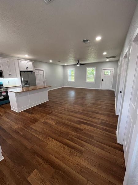Unfurnished living room featuring dark wood-style flooring, a textured ceiling, recessed lighting, and ceiling fan Unfurnished living room featuring dark wood-style flooring, a textured ceiling, recessed lighting, and ceiling fan