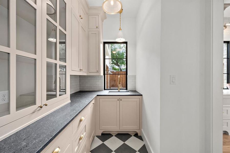 This well-appointed utility area features extensive cabinetry, a black countertop, and a classic black and white checkered floor