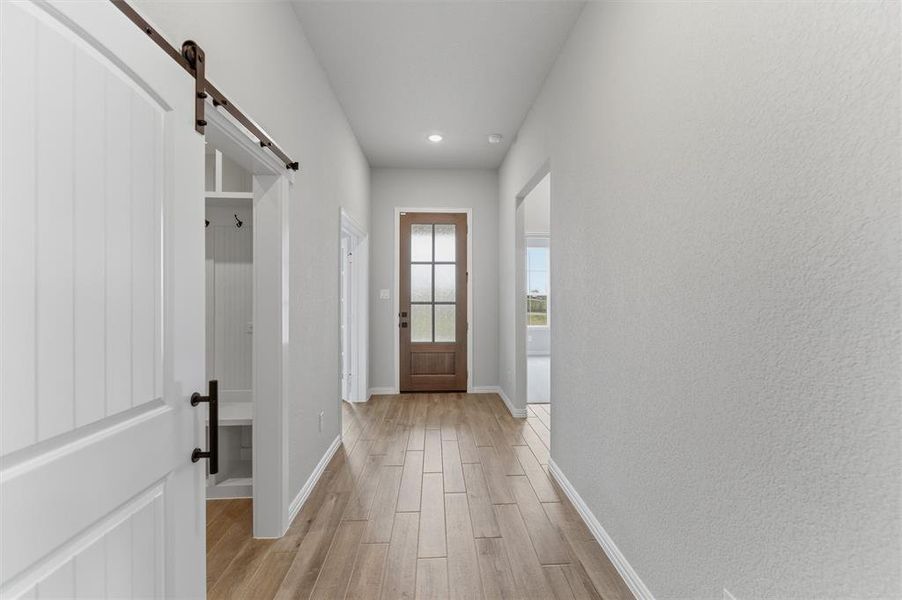 Doorway with a barn door, wood finish floors, and recessed lighting