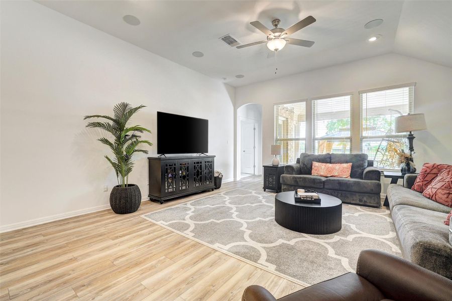 Living room featuring arched walkways, wood finished floors, a ceiling fan, vaulted ceiling, and recessed lighting