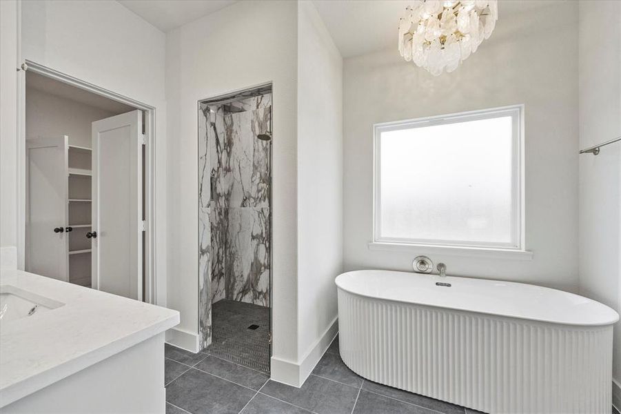 Bathroom with vanity, a notable chandelier, tile patterned floors, and shower with separate bathtub