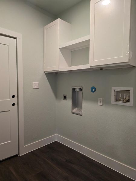 Washroom with dark wood finished floors, hookup for a washing machine, cabinet space, and hookup for an electric dryer