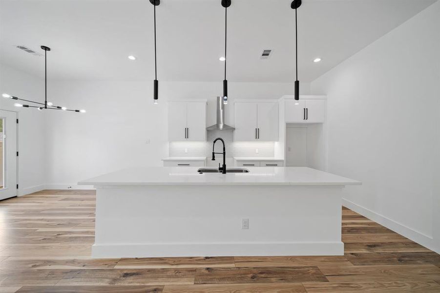 Kitchen with sink, a center island with sink, and white cabinets