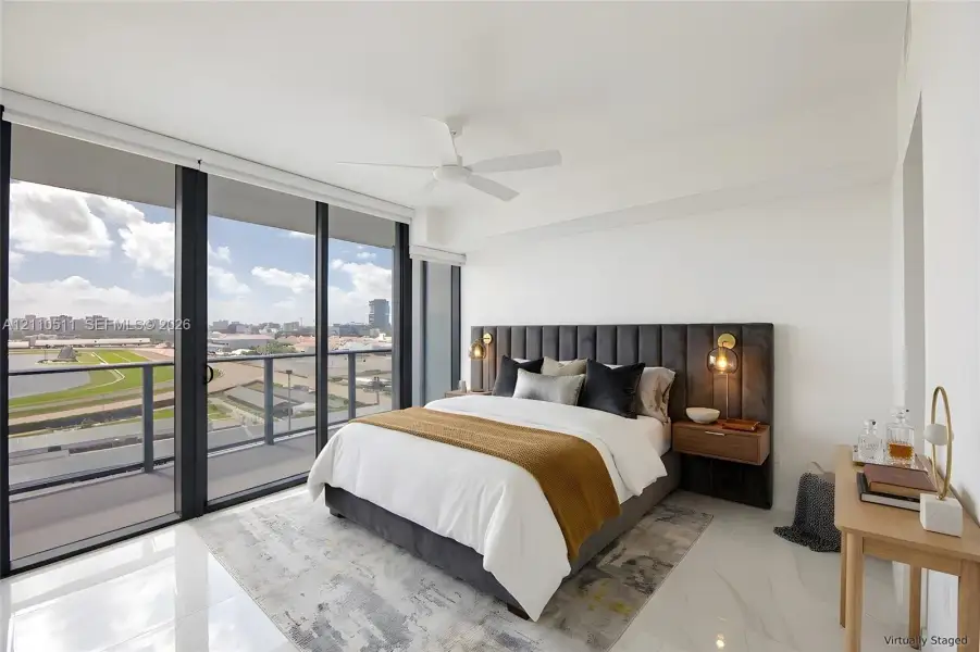 Primary suite with floor-to-ceiling windows, polished tile flooring, wall-mounted wooden bedside tables, integrated bedside lighting, and a white ceiling fan