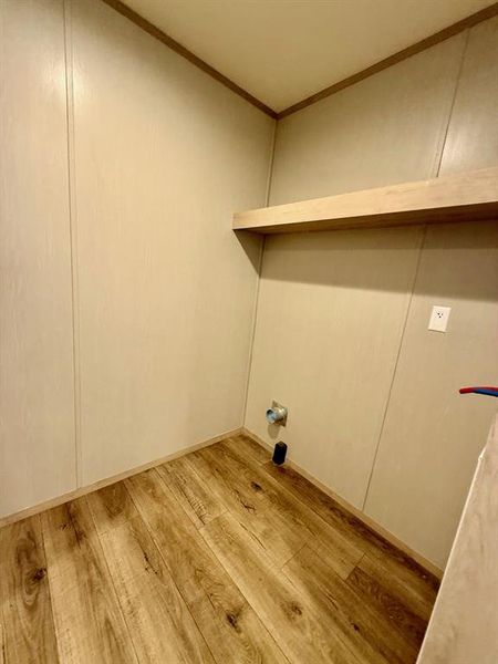 Laundry area with light wood-type flooring and ornamental molding Laundry area with light wood-type flooring and ornamental molding
