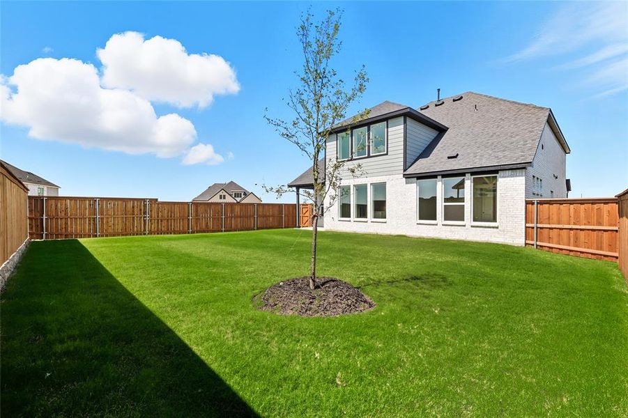 Back of house with a shingled roof, a fenced backyard, and brick siding Back of house with a shingled roof, a fenced backyard, and brick siding
