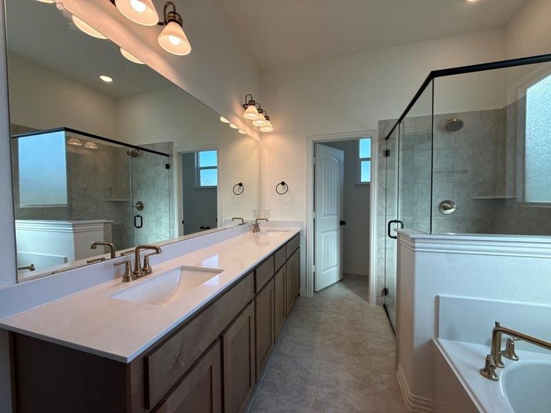 Bathroom featuring double vanity, a stall shower, a bath, and light tile patterned flooring