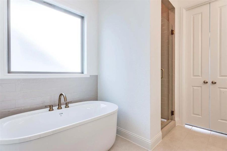 Full bathroom featuring a freestanding tub, a stall shower, and light tile patterned flooring Full bathroom featuring a freestanding tub, a stall shower, and light tile patterned flooring