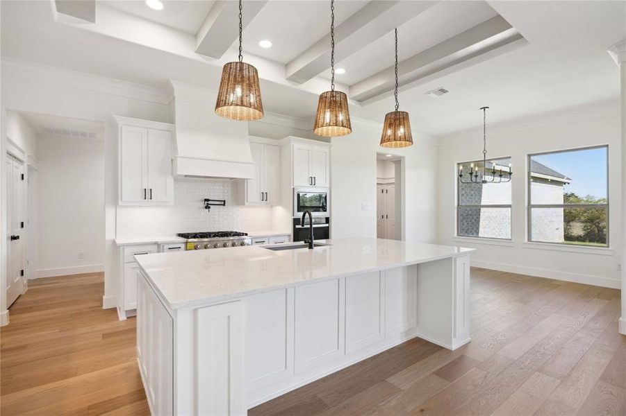 Kitchen with white cabinetry, a kitchen island with sink, and light wood-type flooring