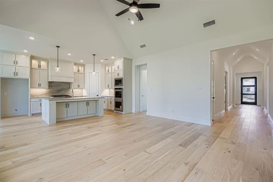 Kitchen featuring high vaulted ceiling, recessed lighting, light wood-style floors, open floor plan, and ceiling fan