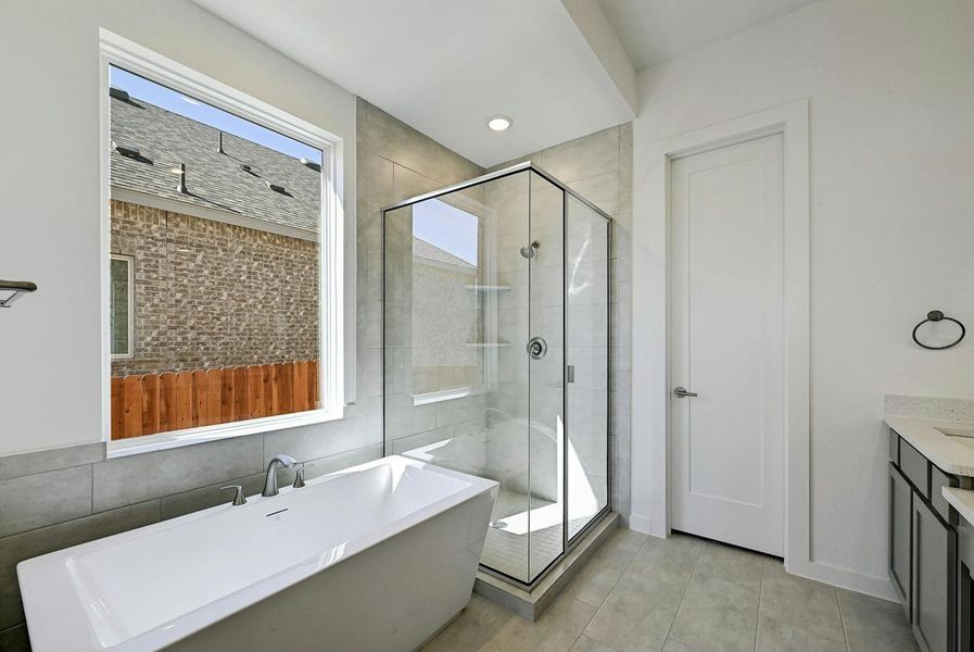 Bathroom with a soaking tub, a shower stall, tile patterned flooring, vanity, and tile walls