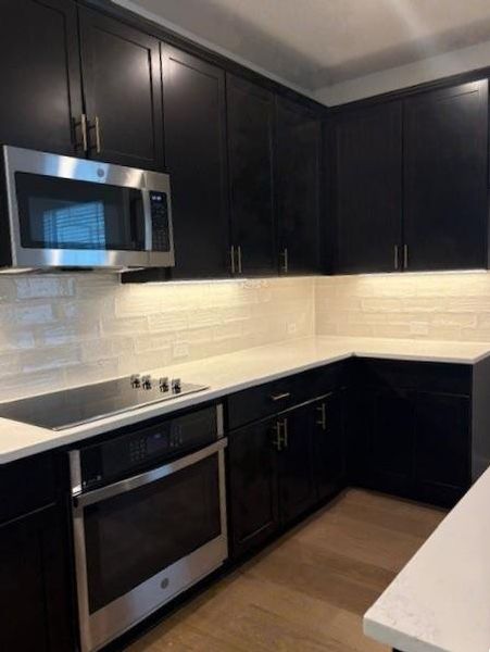 Kitchen featuring light countertops, appliances with stainless steel finishes, and dark cabinetry