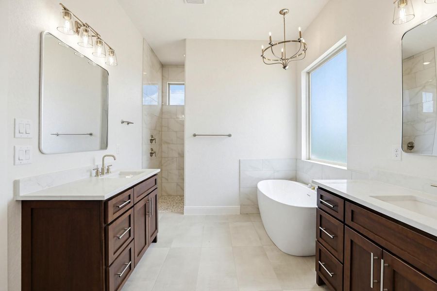 Luxurious primary bathroom featuring a freestanding soaking tub and dual vanities with elegant fixtures.