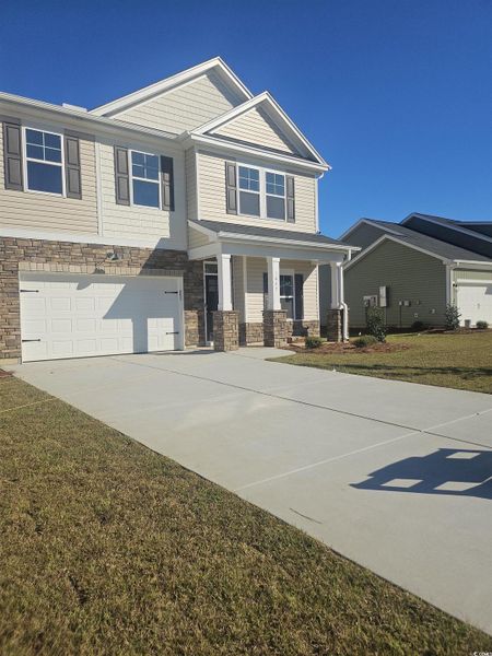 Craftsman-style home featuring stone siding, driveway, covered porch, and a front lawn
