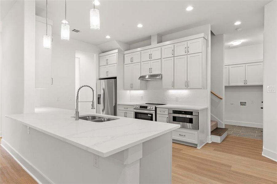 Kitchen with light wood-style floors, a peninsula, white cabinets, and recessed lighting Kitchen with light wood-style floors, a peninsula, white cabinets, and recessed lighting