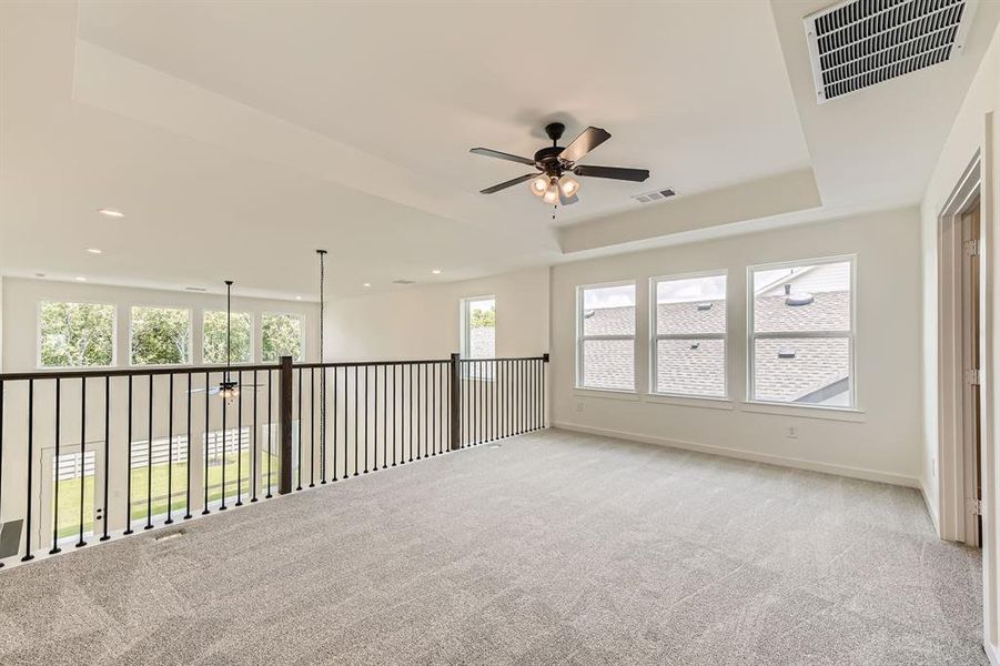 Empty room featuring a tray ceiling, healthy amount of natural light, ceiling fan, light carpet, and recessed lighting Empty room featuring a tray ceiling, healthy amount of natural light, ceiling fan, light carpet, and recessed lighting
