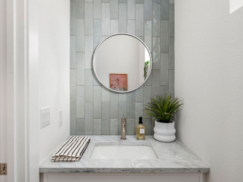 A well-appointed vanity with a sleek sink and tiled accent wall adds modern elegance.