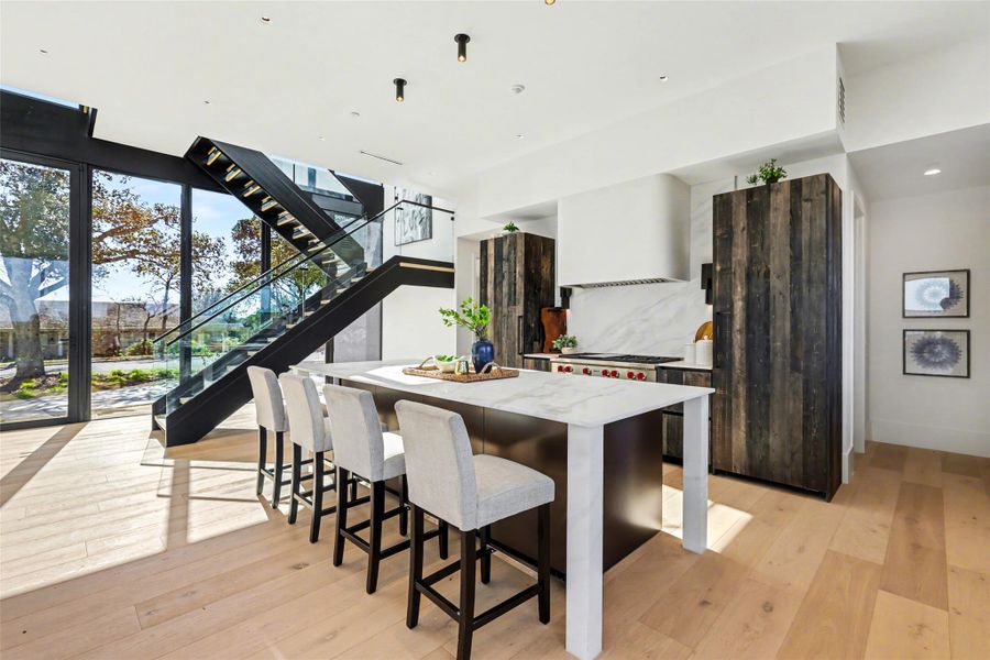 Kitchen with a center island, a kitchen bar, light wood-style flooring, modern cabinets, and light stone counters