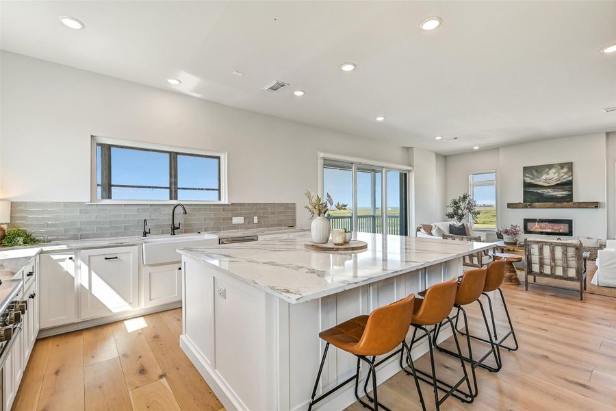The chef’s kitchen blends luxury and functionality with Thermador appliances, quartz counters, farmhouse sink, oversized island seating, and a 6 burner double oven. Open sightlines to the dining and living areas make this the true heart of the home.